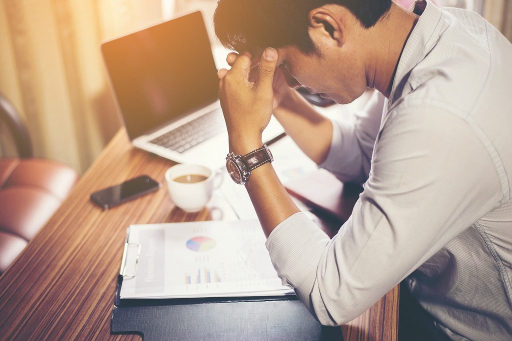 stressed worker sitting at desk hands on forehead outsource HR