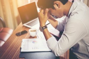 stressed worker sitting at desk hands on forehead outsource HR